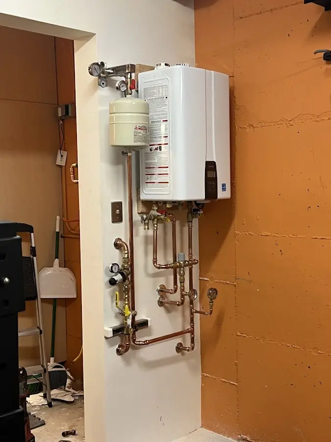Plumbing technician inspecting water heater connections in Roslyn